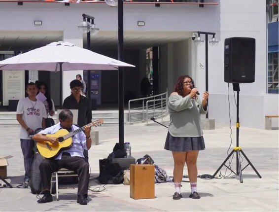 Gustavo Adolfo Urbina Ruiz en la guitarra acompaña a una de las cantantes en la explanada de Letras.